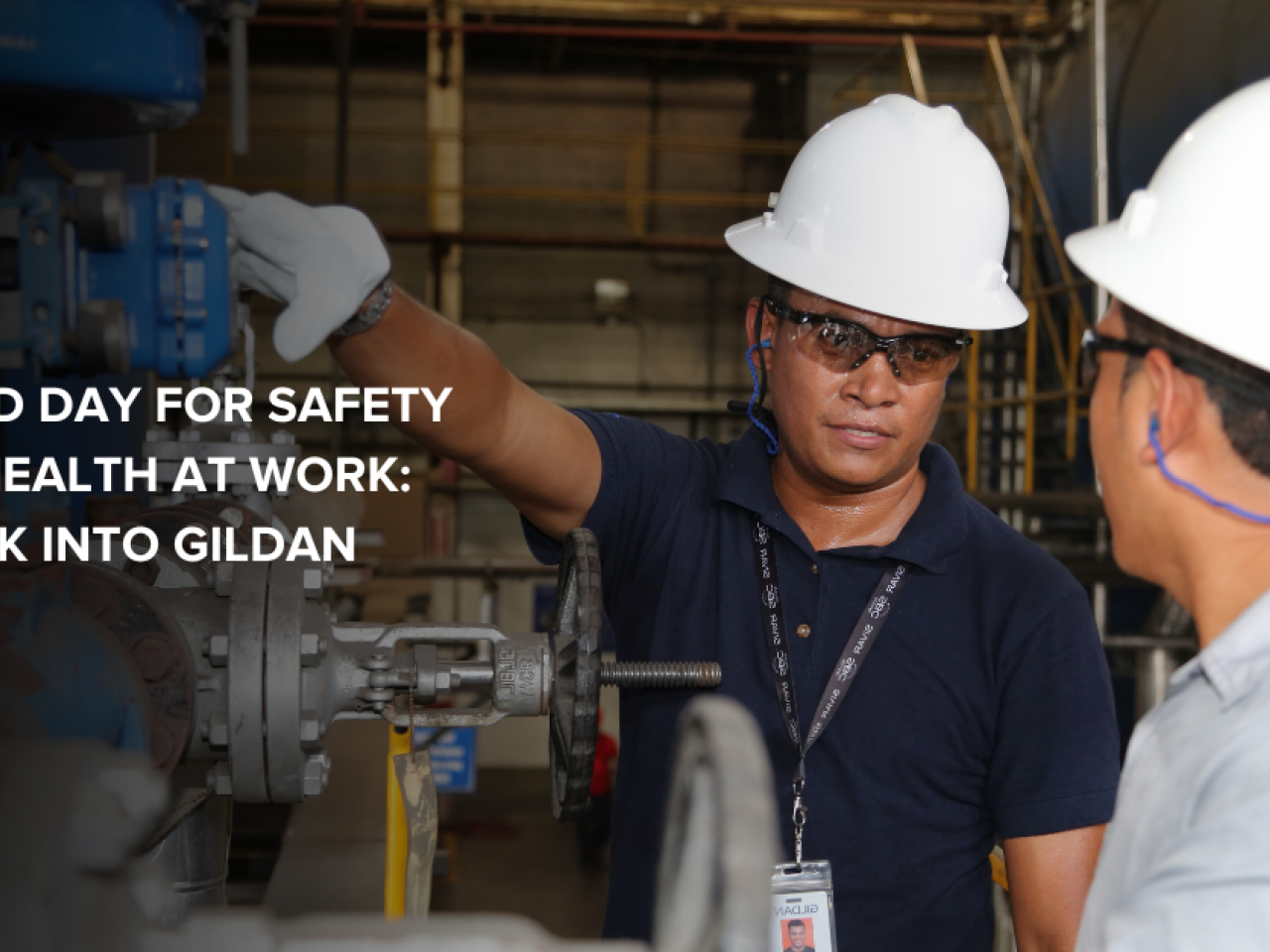 两位Gildan员工身着安全设备,在工厂楼层交互