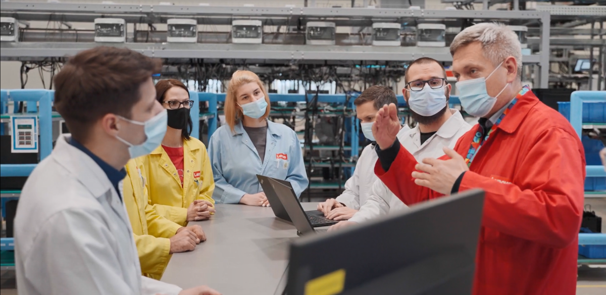 小群人聚在一张表上,都戴保护面罩和不同颜色的实验大衣笔记本机开表工厂机器背后