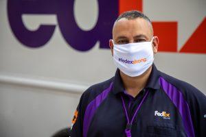 穿制服员工站在FedEx卡车前戴面罩表示#fedex强